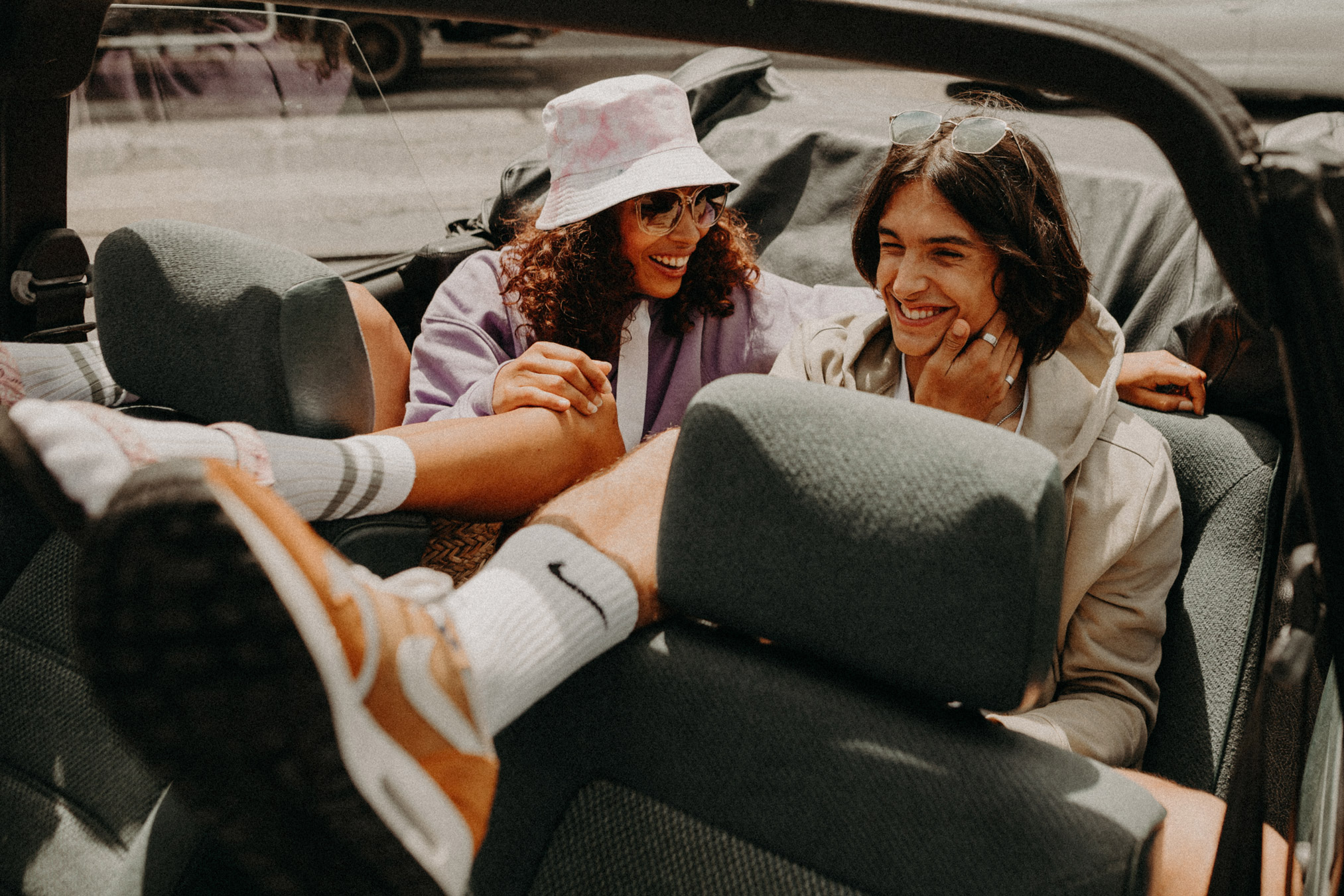 Deux jeunes souriants dans un cabriolet pour la marque Gertrude.