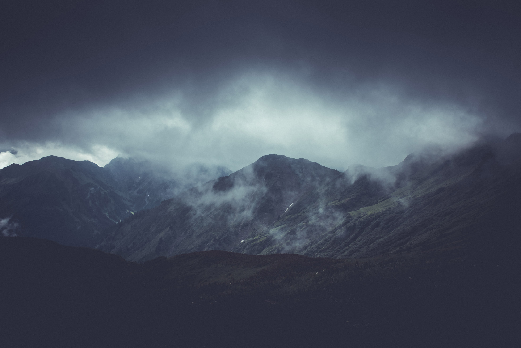 Paysage montagneux avec des nuages, sans neige, illustrant l'atmosphère de Snowfall Studio.